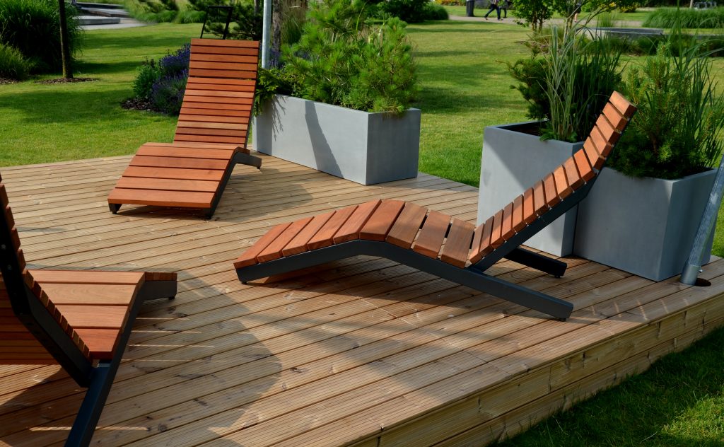 rocking chair on the pavement under the trees in the square. wooden deck chairs made of tropical wood for one person in the park. They are comfortable made of brown planks, slats steel frames, pine, backrest, bench, restaurant, pub, cafe, spa